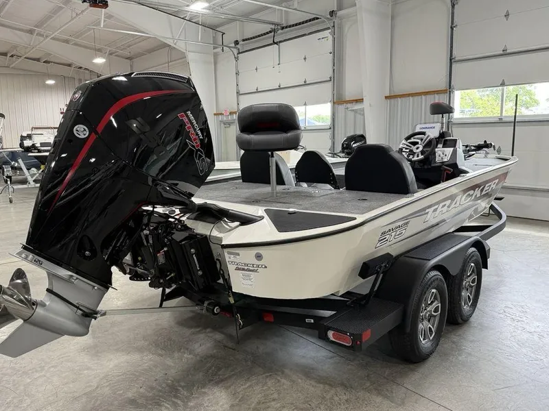 Slide: The Image of 2025 Tracker Savage 215 boat in showroom, featuring powerful outboard motor and dual-axle trailer. - 4