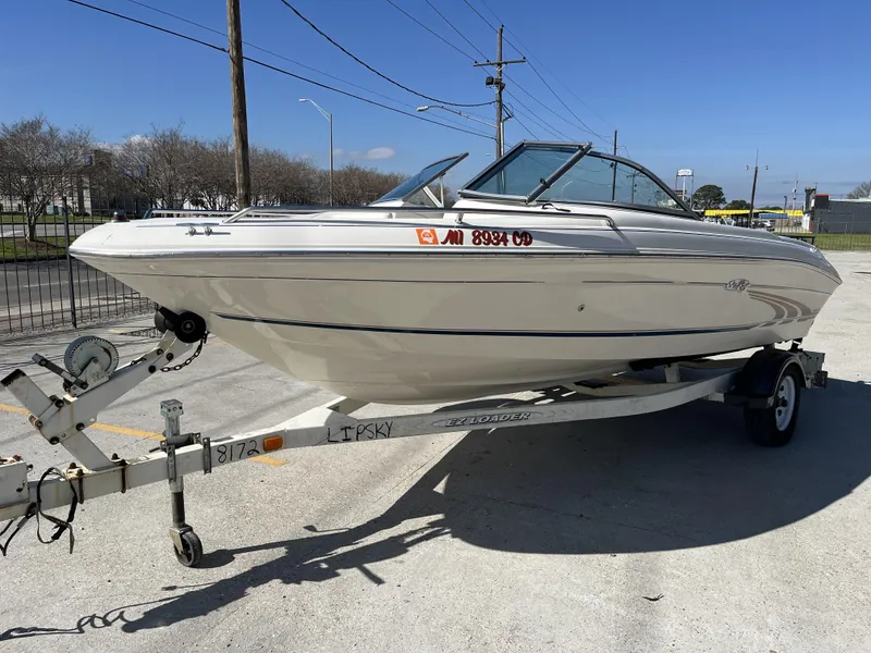 Slide: The Image of 1997 Sea Ray 185 boat on trailer, parked outdoors under clear blue sky. - 10
