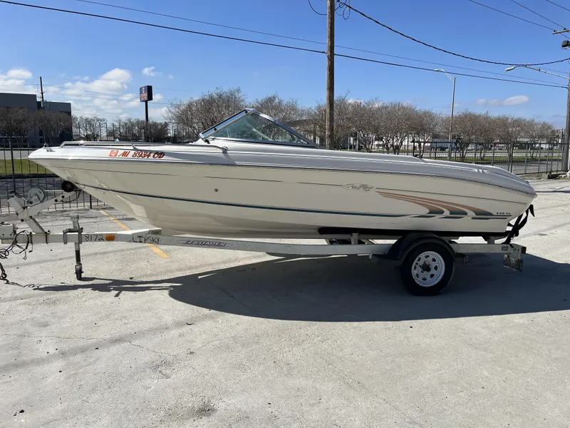 Slide: The Image of 1997 Sea Ray 185 boat on trailer, parked outdoors under clear sky. - 3