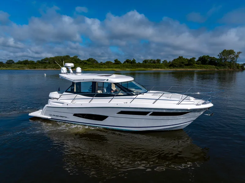 Slide: The Image of 2021 Regal 38 Grande Coupe cruising on a calm lake under a blue sky. - 0