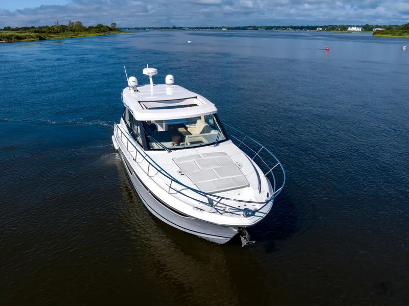 Slide: The Image of 2021 Regal 38 Grande Coupe cruising on a serene waterway under a blue sky. - 12
