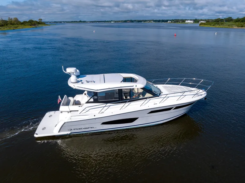 Slide: The Image of 2021 Regal 38 Grande Coupe cruising on a calm river under a partly cloudy sky. - 13