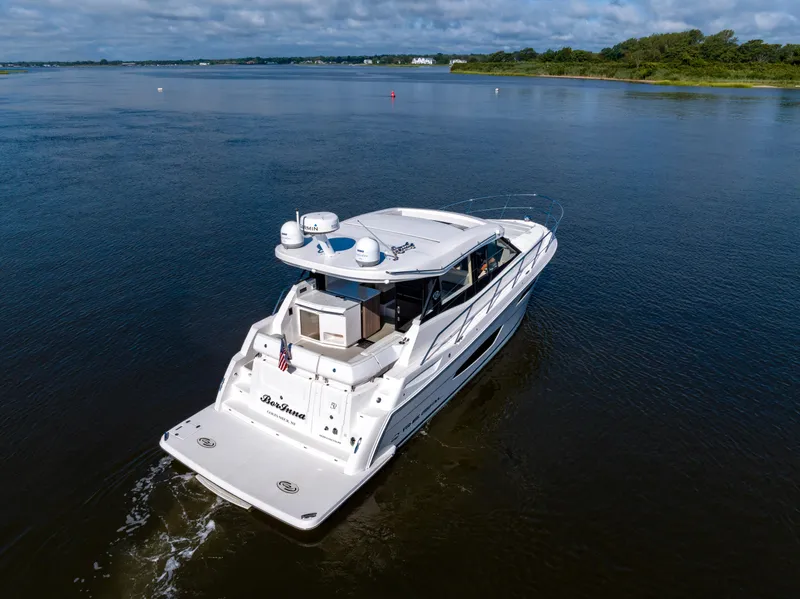 Slide: The Image of 2021 Regal 38 Grande Coupe cruising on a calm lake under a cloudy sky. - 14