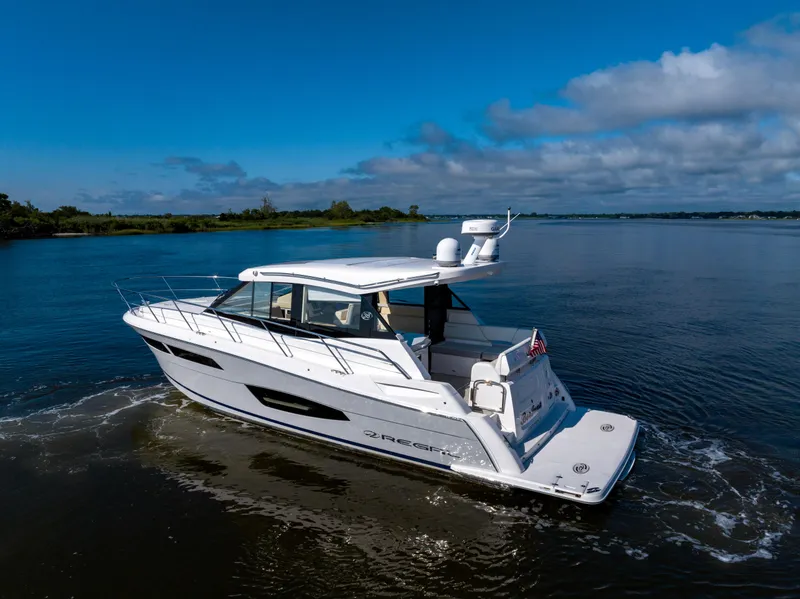 Slide: The Image of 2021 Regal 38 Grande Coupe cruising on a calm lake under a clear blue sky. - 17