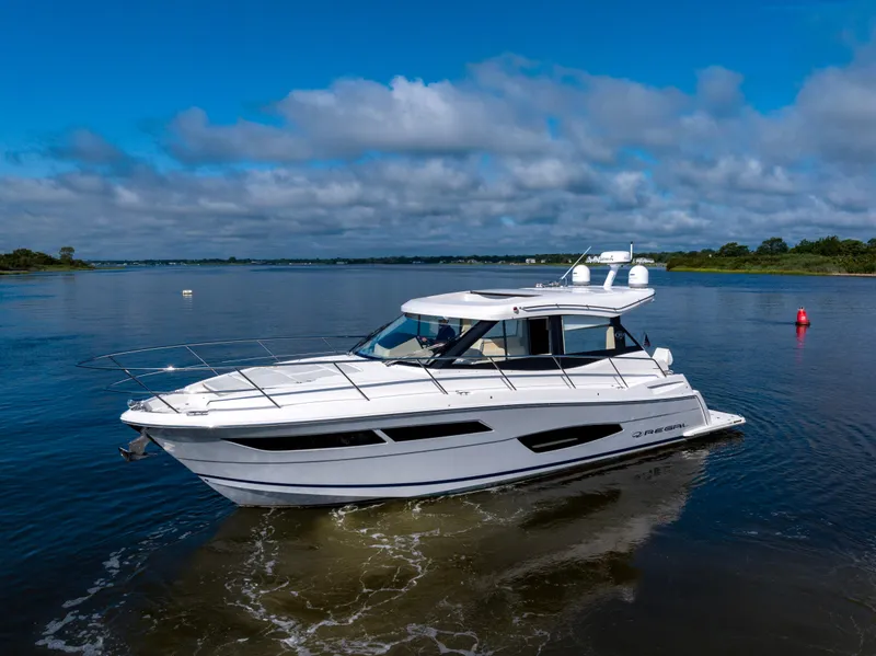 Slide: The Image of 2021 Regal 38 Grande Coupe yacht cruising on a calm lake under a blue sky. - 19