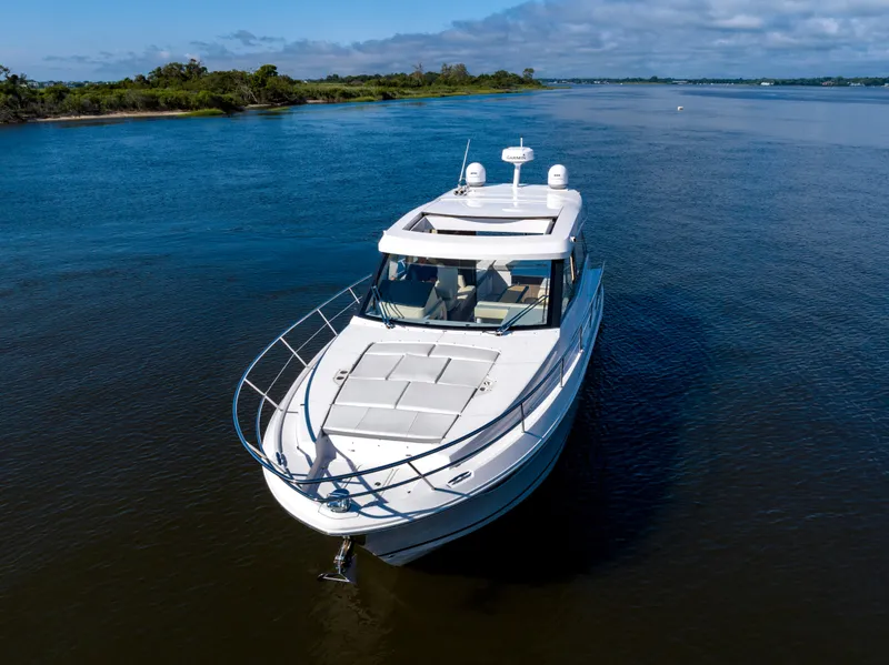 Slide: The Image of 2021 Regal 38 Grande Coupe cruising on a serene river under a clear sky. - 22