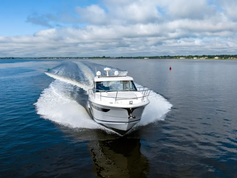 Slide: The Image of 2021 Regal 38 Grande Coupe cruising on a calm lake under a cloudy sky. - 30