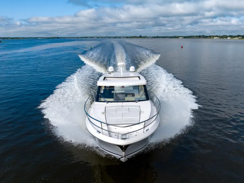 Slide: The Image of 2021 Regal 38 Grande Coupe cruising on open water, creating a dynamic wake. - 32