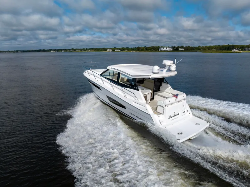 Slide: The Image of 2021 Regal 38 Grande Coupe cruising on a calm lake under a cloudy sky. - 33