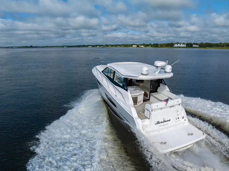 Slide: The Image of 2021 Regal 38 Grande Coupe cruising on open water under a cloudy sky. - 34