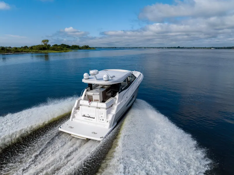 Slide: The Image of 2021 Regal 38 Grande Coupe cruising on a serene lake under a partly cloudy sky. - 35