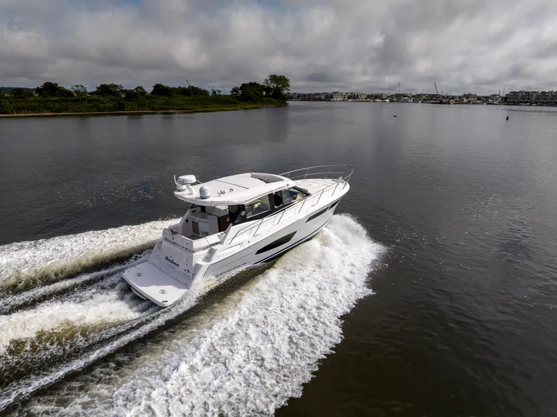 Slide: The Image of 2021 Regal 38 Grande Coupe cruising on a calm river under cloudy skies. - 36