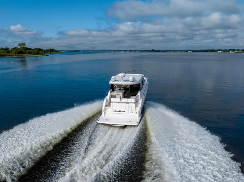 Slide: The Image of 2021 Regal 38 Grande Coupe cruising on a serene lake under a cloudy sky. - 38