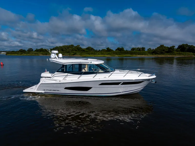 Slide: The Image of 2021 Regal 38 Grande Coupe cruising on a calm lake under a blue sky. - 4