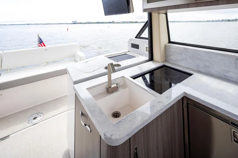 Slide: The Image of 2021 Regal 38 Grande Coupe yacht kitchen with sink and stovetop, overlooking water. - 48