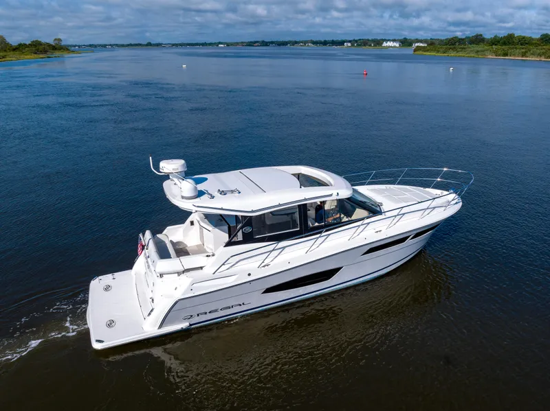 Slide: The Image of 2021 Regal 38 Grande Coupe cruising on a serene lake under a partly cloudy sky. - 5
