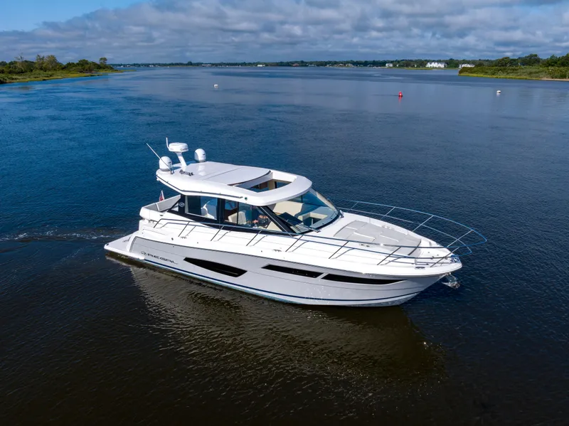 Slide: The Image of 2021 Regal 38 Grande Coupe cruising on a serene lake under a partly cloudy sky. - 6