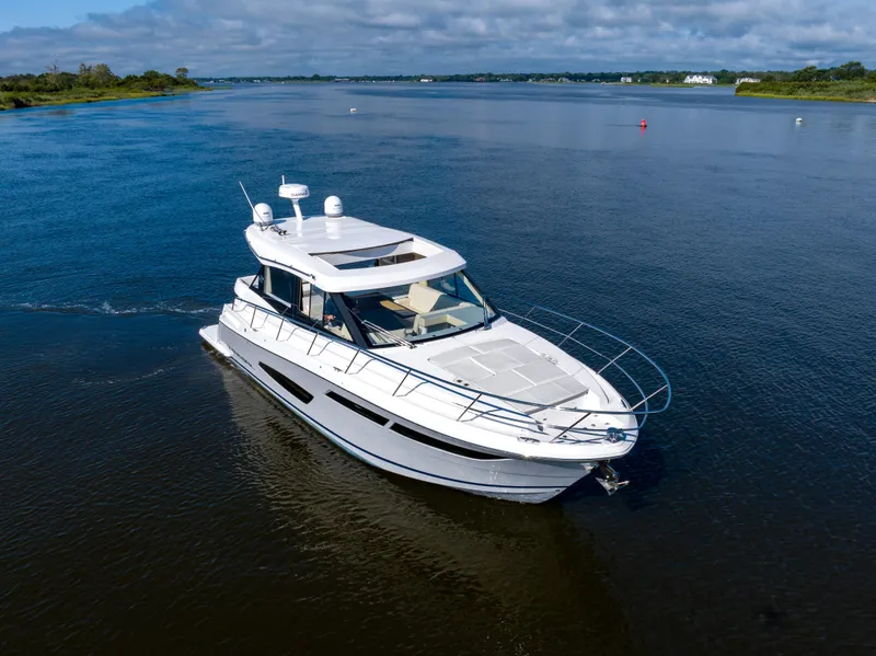 Slide: The Image of 2021 Regal 38 Grande Coupe cruising on a serene waterway under a partly cloudy sky. - 7