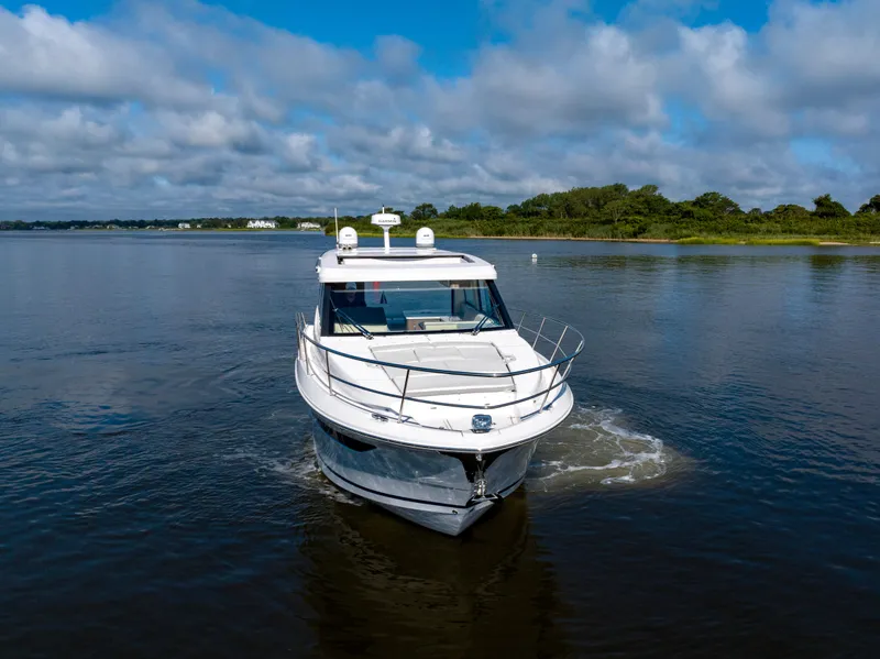 Slide: The Image of 2021 Regal 38 Grande Coupe cruising on a calm lake under a blue sky. - 9