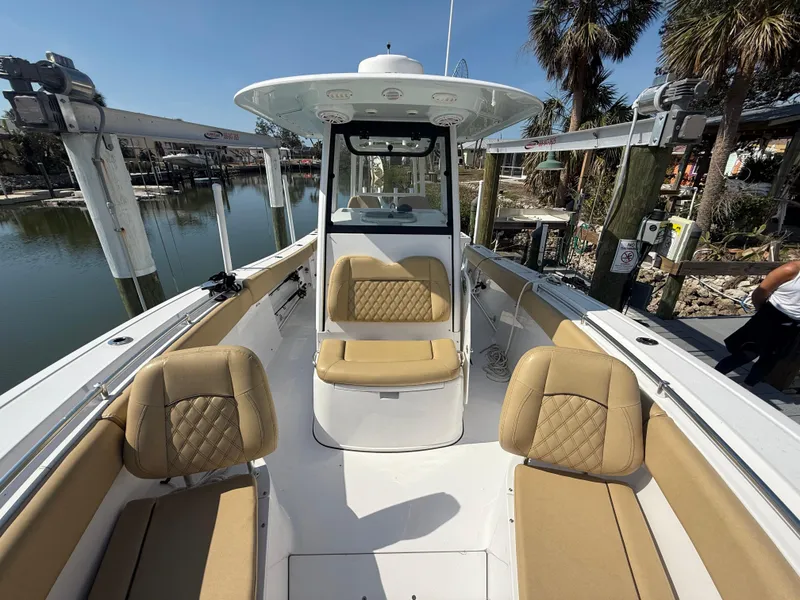 Slide: The Image of 2023 Sportsman Open 282 Center Console boat with tan seating, docked near palm trees. - 45