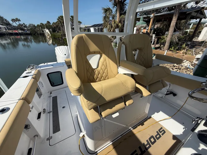 Slide: The Image of 2023 Sportsman Open 282 Center Console boat with tan seating, docked by a serene waterfront. - 38