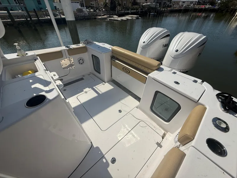 Slide: The Image of 2023 Sportsman Open 282 Center Console boat interior with twin engines, docked by the water. - 10