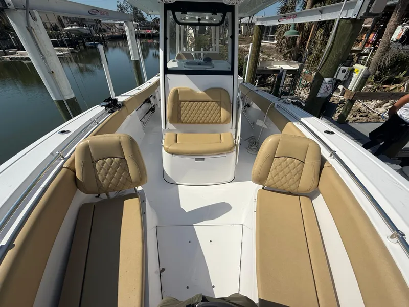 Slide: The Image of 2023 Sportsman Open 282 Center Console boat with tan seating, docked by the water. - 46