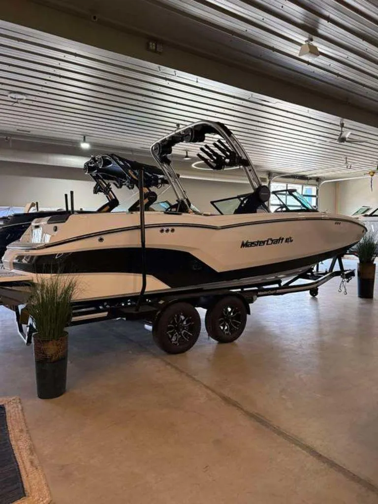 Slide: The Image of 2025 MasterCraft NXT24 boat on trailer in showroom setting. - 6