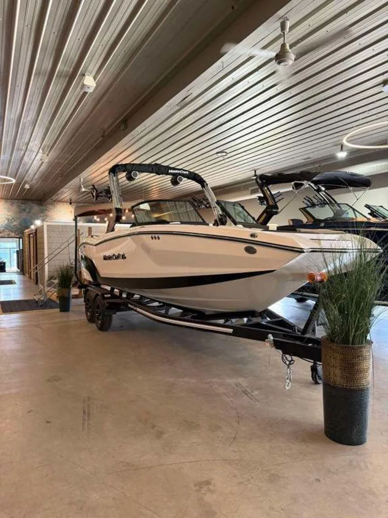 Slide: The Image of 2025 MasterCraft NXT24 boat displayed indoors on a trailer. - 7