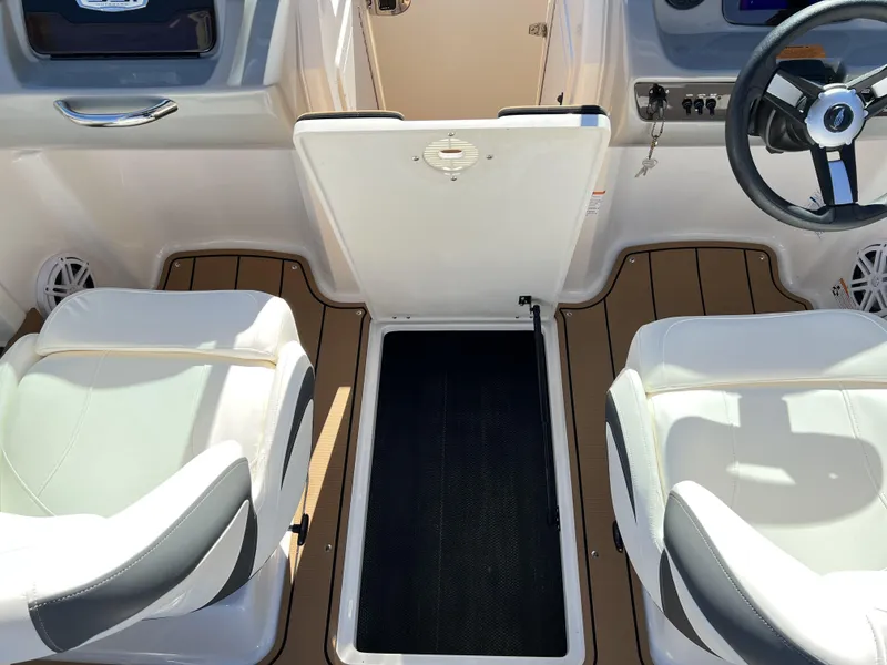 Slide: The Image of 2023 Chaparral 21SSi OB SPORT boat interior with white seats and open storage compartment. - 6