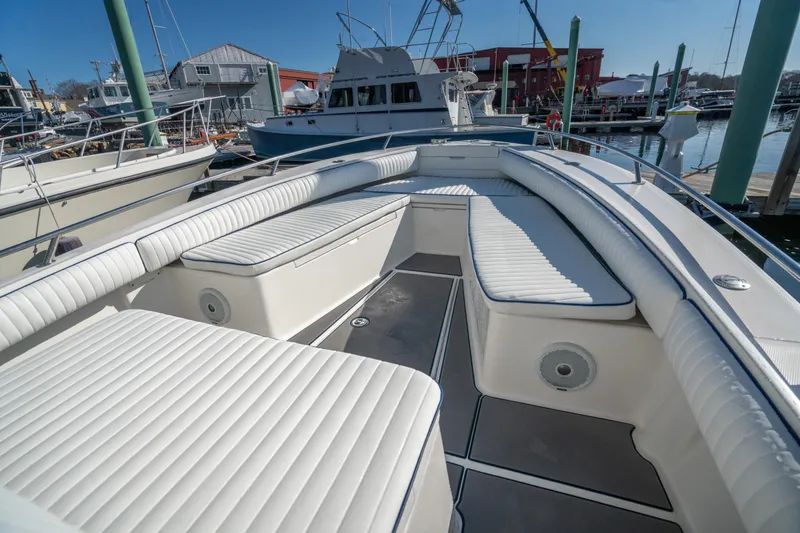 Slide: The Image of 2003 Regulator 26 Forward Seating boat with spacious white cushioned seating in a marina. - 18