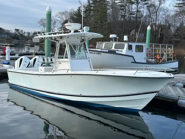 Slide: The Image of 2003 Regulator 26 Forward Seating boat docked in a marina, surrounded by calm water. - 7