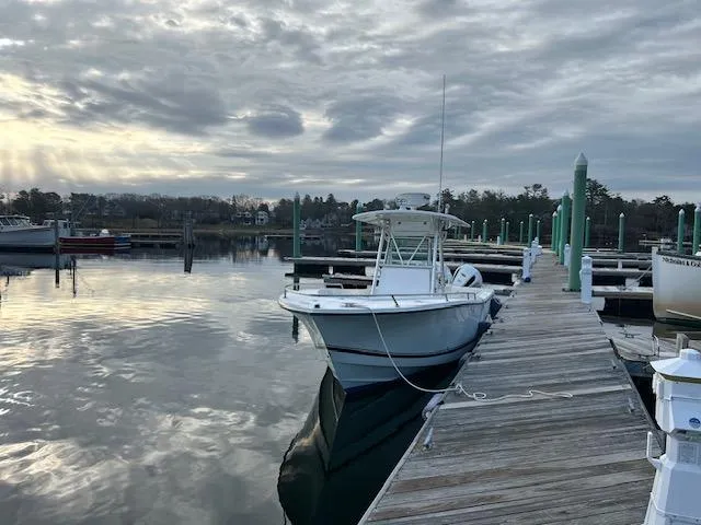 Slide: The Image of 2003 Regulator 26 Forward Seating boat docked at a serene marina under cloudy skies. - 8