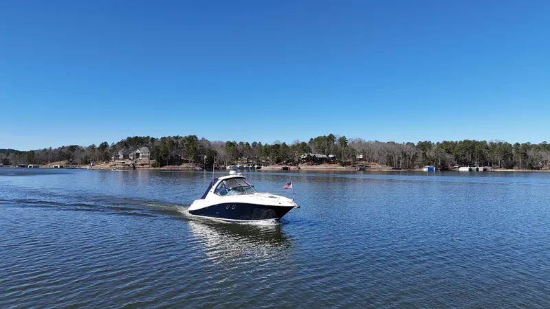 Slide: The Image of 2007 Sea Ray 310 Sundancer cruising on a serene lake under a clear blue sky. - 10