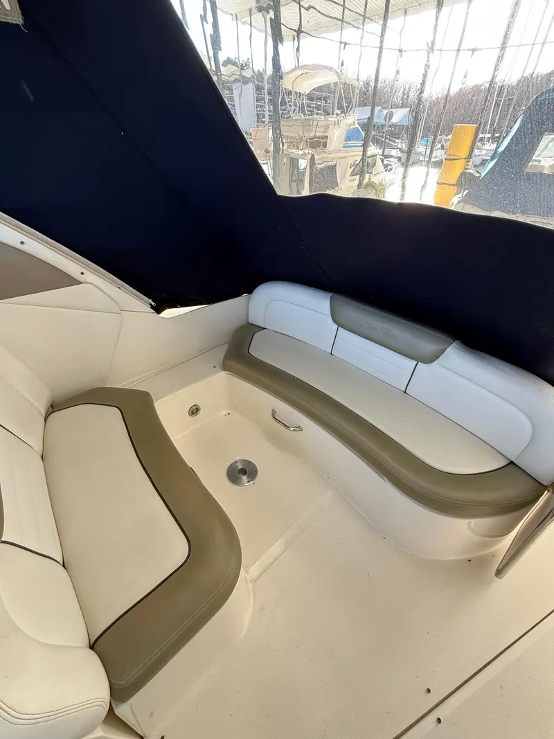 Slide: The Image of 2007 Sea Ray 310 Sundancer interior seating area with cushioned benches and dark canopy. - 17