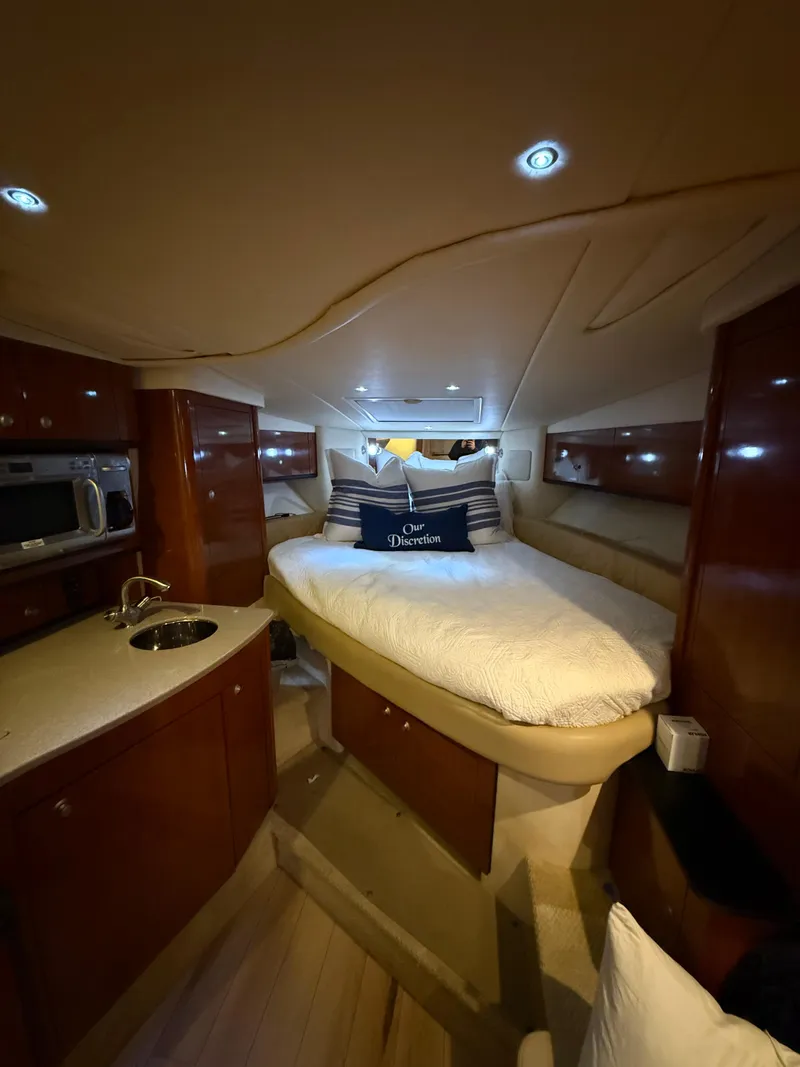 Slide: The Image of 2007 Sea Ray 310 Sundancer cabin interior with bed, kitchenette, and wood cabinetry. - 21