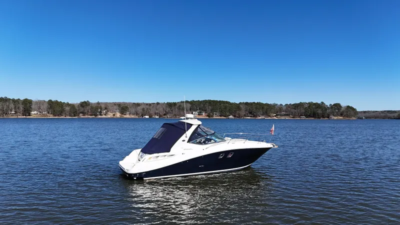 Slide: The Image of 2007 Sea Ray 310 Sundancer boat on a calm lake under clear blue skies. - 3