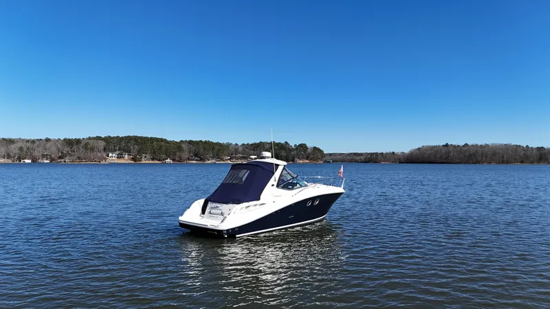 Slide: The Image of 2007 Sea Ray 310 Sundancer boat on a calm lake under clear blue skies. - 4