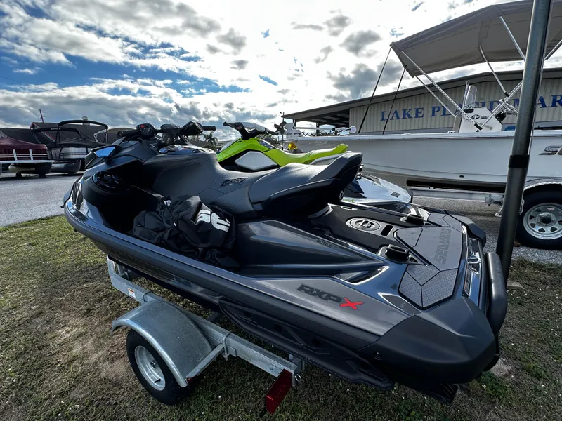 Slide: The Image of 2023 Sea-Doo RXP-X 300 jet ski on trailer, parked outdoors. - 2
