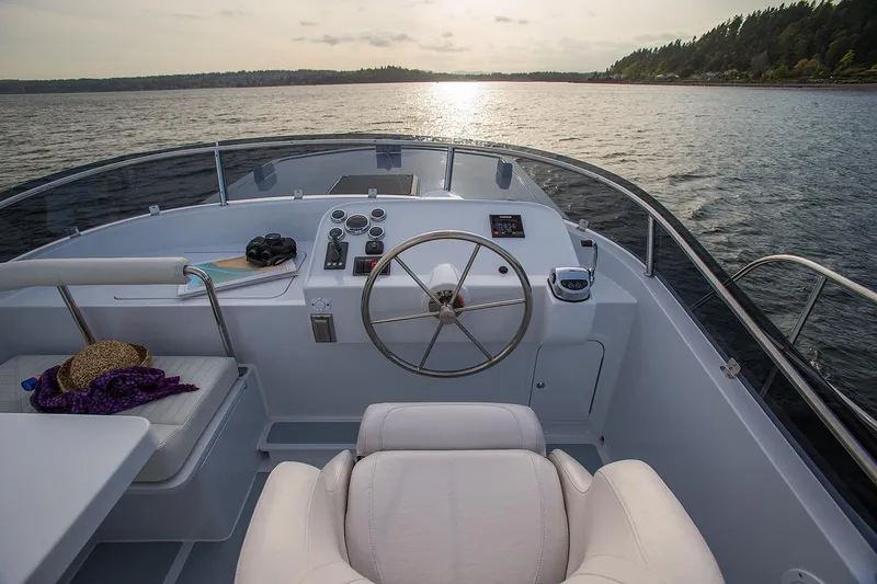 Slide: The Image of Helmsman Trawlers 38E Pilothouse 2026, serene cockpit view at sunset on open water. - 10