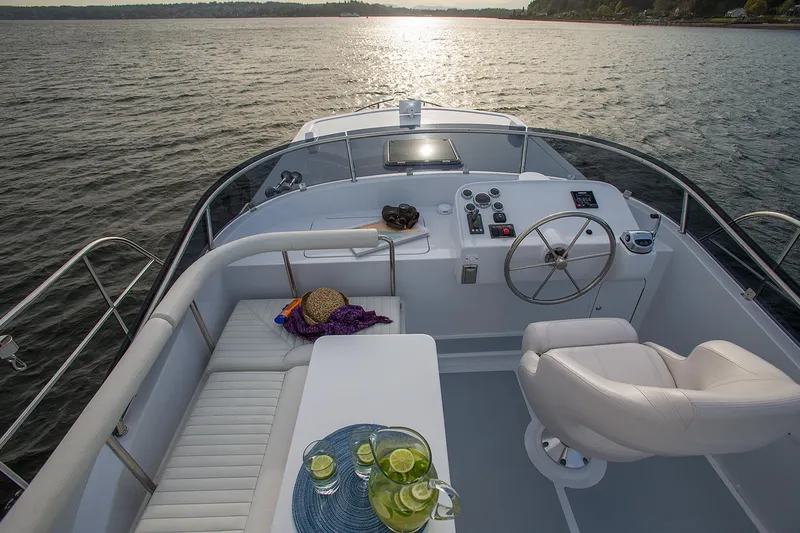 Slide: The Image of Helmsman Trawlers 38E Pilothouse 2026, elegant deck view with seating and steering, on serene water. - 11