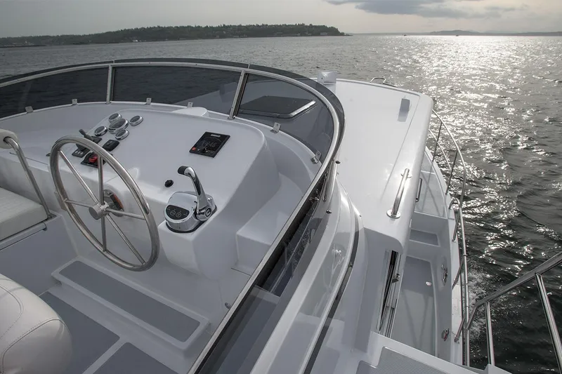 Slide: The Image of 2026 Helmsman Trawlers 38E Pilothouse on water, showcasing helm and controls. - 15