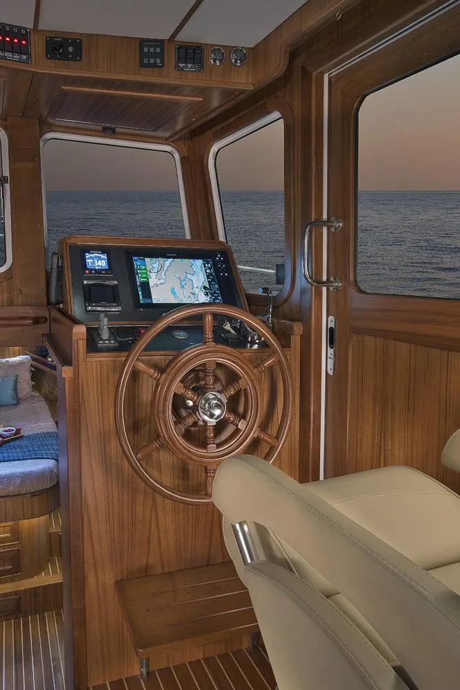 Slide: The Image of 2026 Helmsman Trawlers 38E Pilothouse interior with wooden helm and navigation equipment. - 28