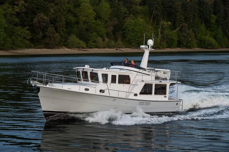 Slide: The Image of 2026 Helmsman Trawlers 38E Pilothouse cruising on a scenic waterway. - 3