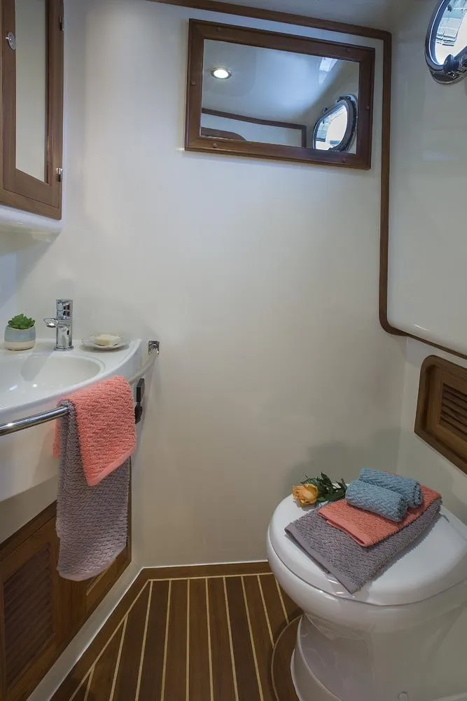 Slide: The Image of Helmsman Trawlers 38E Pilothouse 2026 bathroom with sink, mirror, and toilet. - 33