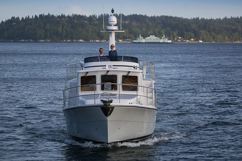 Slide: The Image of 2026 Helmsman Trawlers 38E Pilothouse cruising on a scenic waterway. - 5