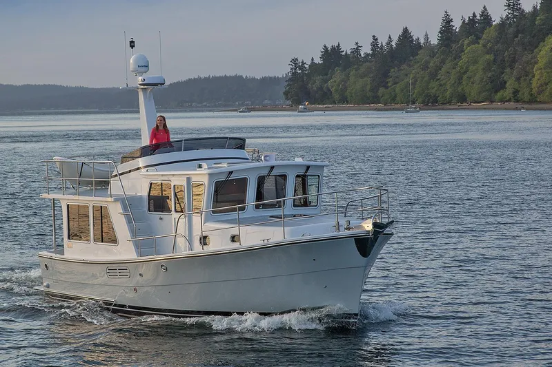 Slide: The Image of 2026 Helmsman Trawlers 38E Pilothouse cruising on a serene waterway. - 6