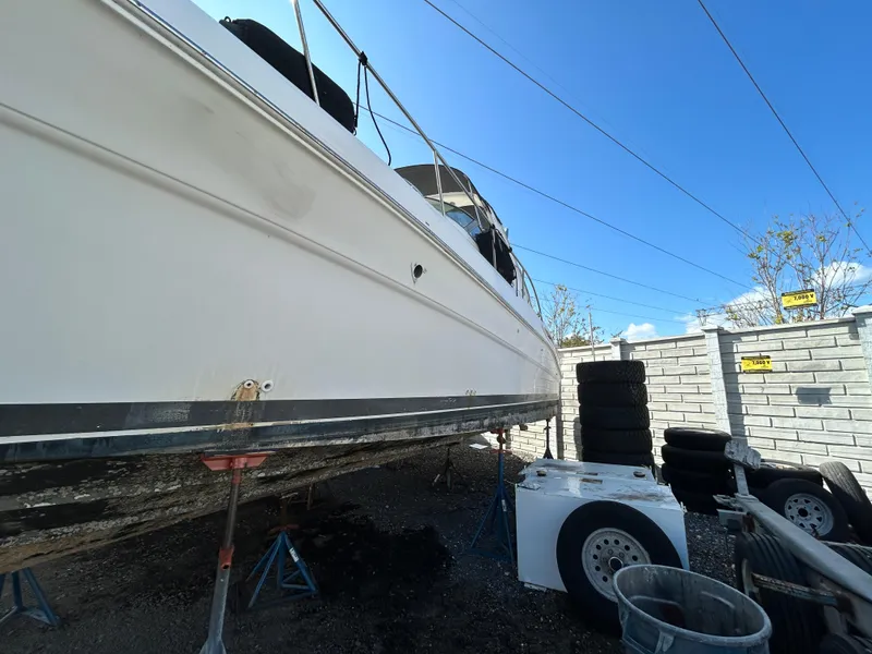 Slide: The Image of 2002 Sea Ray 340 Sundancer boat on stands, outdoor storage, clear blue sky. - 13