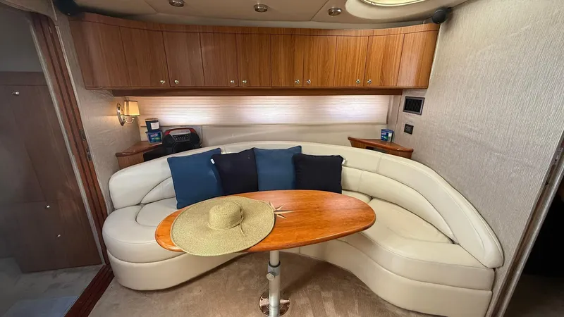 Slide: The Image of 2003 Regal Commodore 4260 yacht interior with curved seating, wooden table, and cushions. - 13