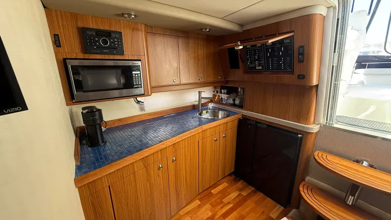 Slide: The Image of 2003 Regal Commodore 4260 yacht kitchen with wood cabinets, microwave, sink, and mini fridge. - 14